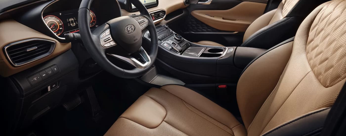 The brown and black interior of a 2023 Hyundai Santa Fe for sale shows the steering wheel and center console.