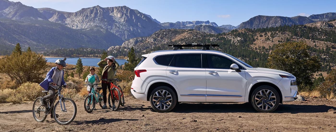 A white 2023 Hyundai Santa Fe is shown from the side near a remote bike path.