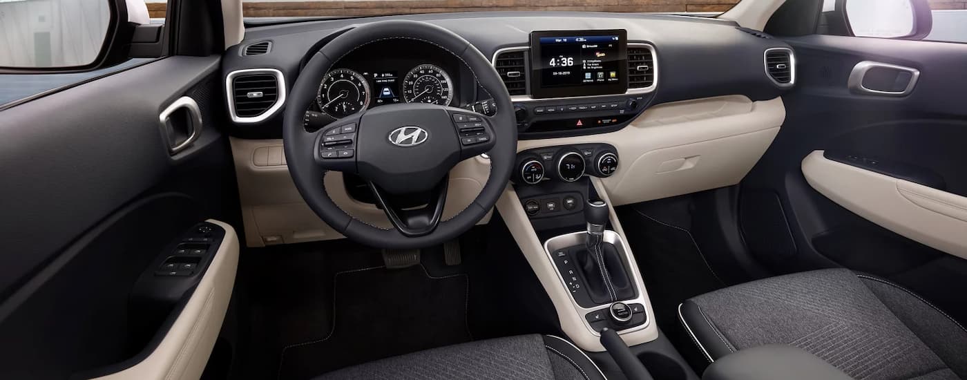 The grey and tan interior of a 2022 Hyundai Venue shows the steering wheel and center console.