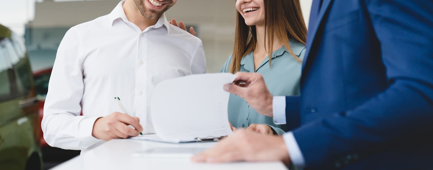 A person is shown filling out paperwork for a Bankruptcy Auto loan.