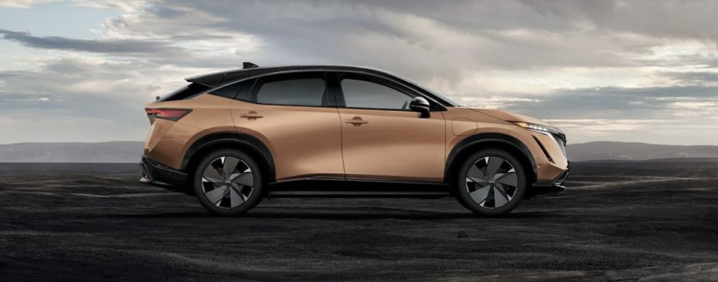 A gold 2023 Nissan Ariya is shown from the side.