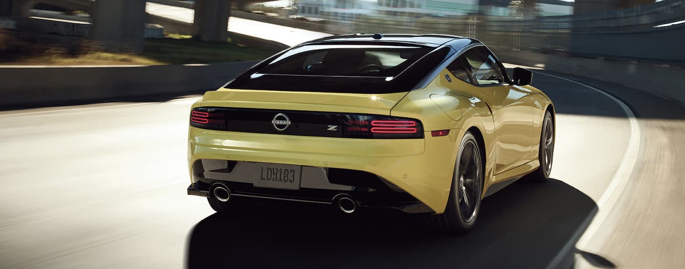 A yellow 2023 Nissan Z is shown from the rear driving on an open road.
