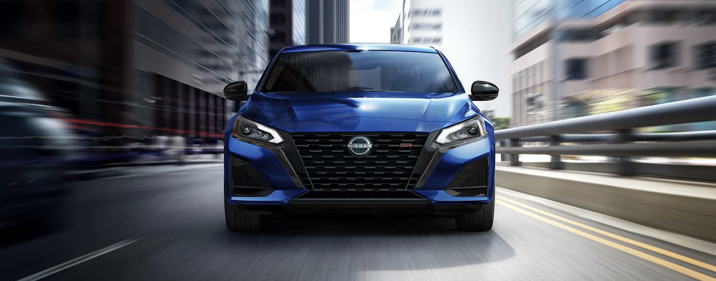 A blue 2023 Nissan Altima SR is shown from the front driving on an open road after leaving a Nissan dealer Edmonton.