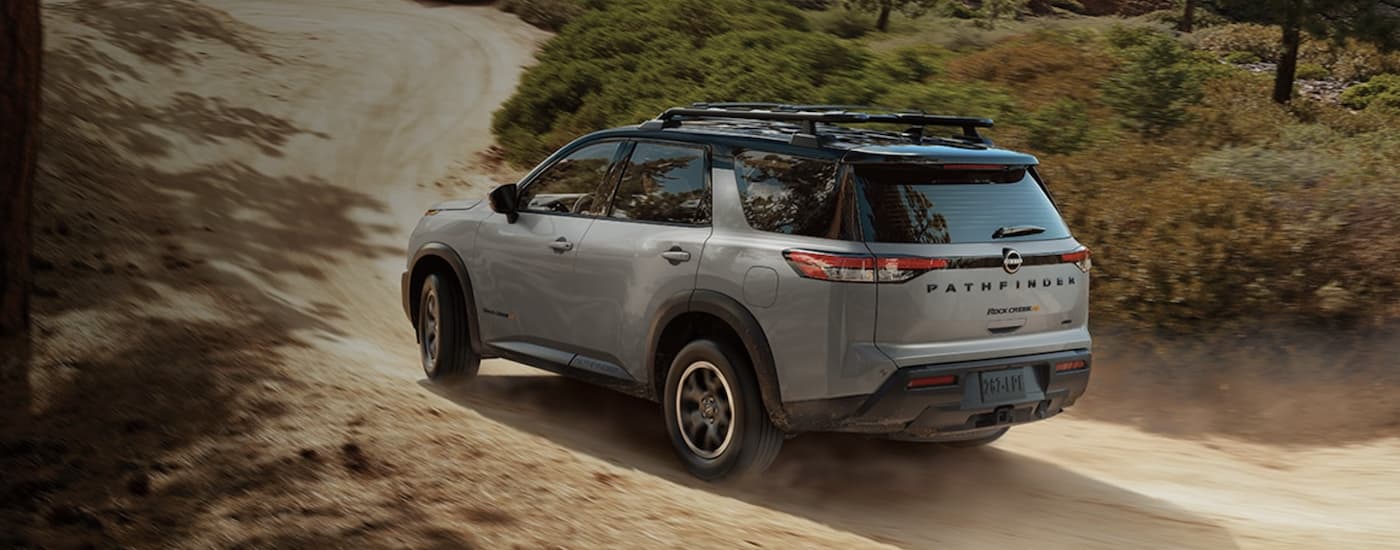 A grey 2023 Pathfinder Rock Creek is shown from the rear driving on a dirt road.