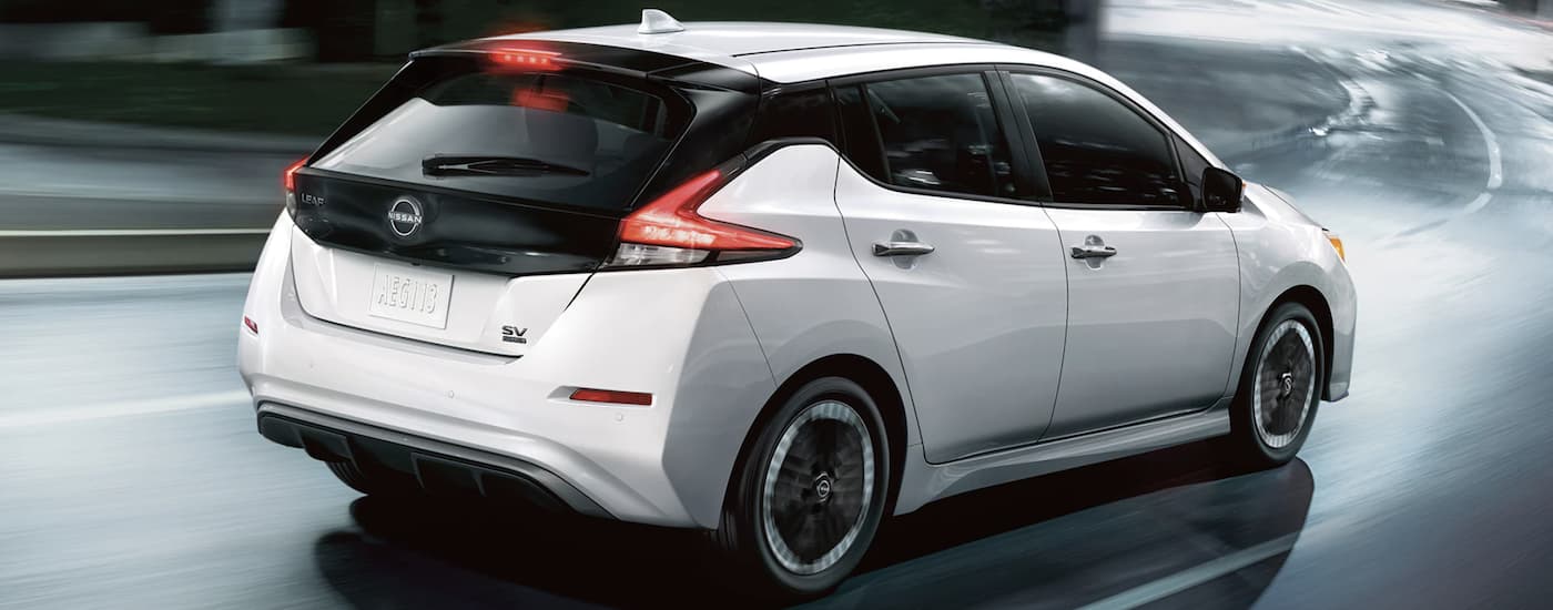 A white 2023 Nissan LEAF SV is shown driving on an open road.