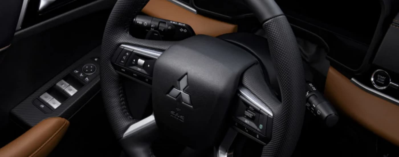 The black and brown interior of a 2022 Mitsubishi Outlander shows the steering wheel.