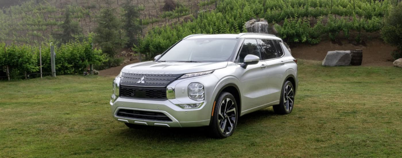 A white 2022 Mitsubishi Outlander for sale, is shown parked in a field.