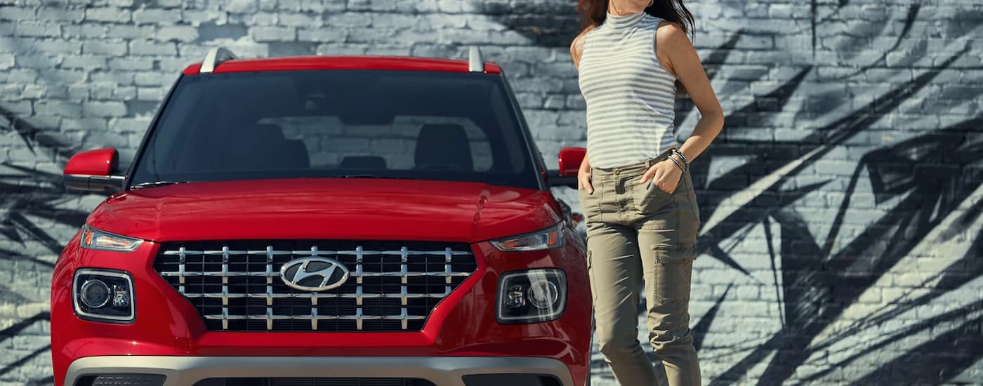 A woman is shown walking away from a red 2022 Hyundai Venue.