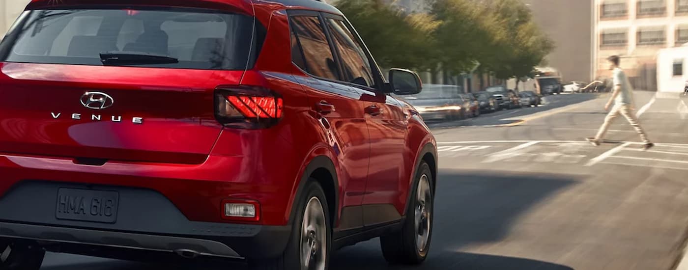 A red 2022 Hyundai Venue is shown driving on a city street.
