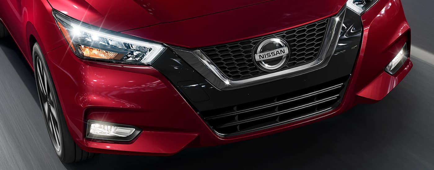 The front of a red 2022 Nissan Altima is shown while it's driving on a highway.