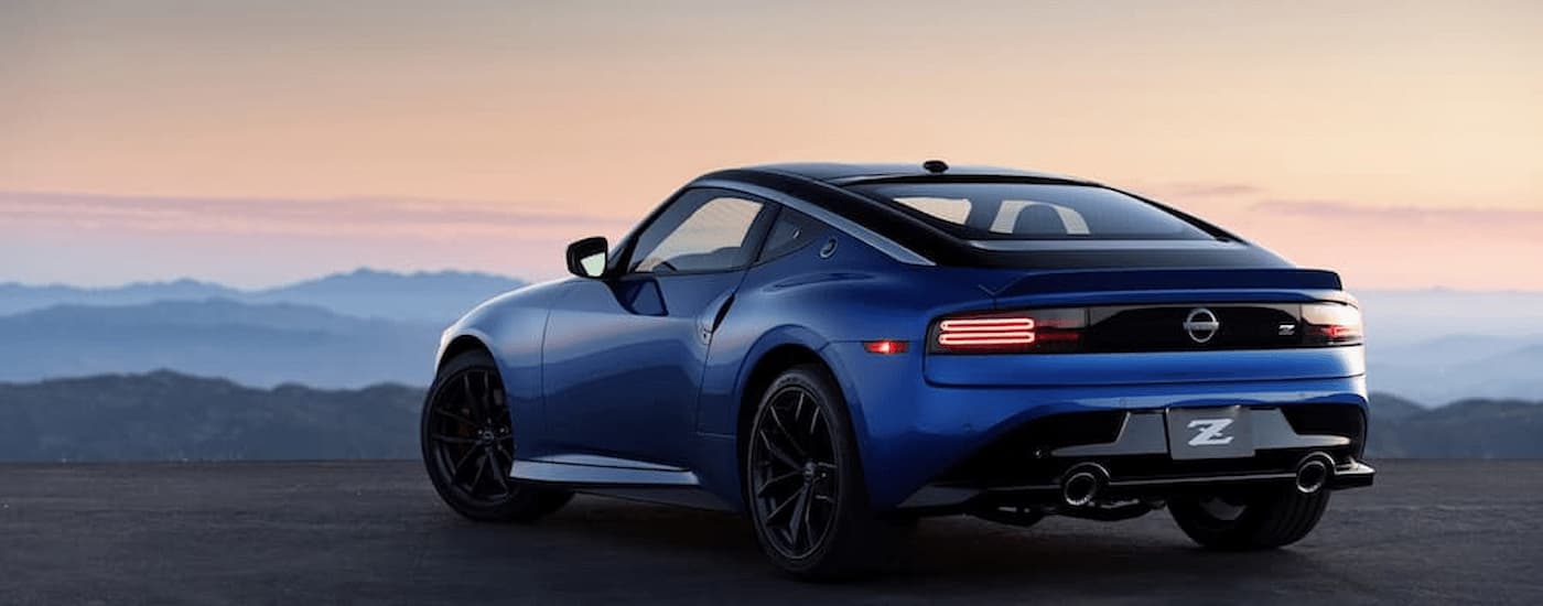 A blue 2023 Nissan Z is shown from a rear angle parked on an open paved lot.