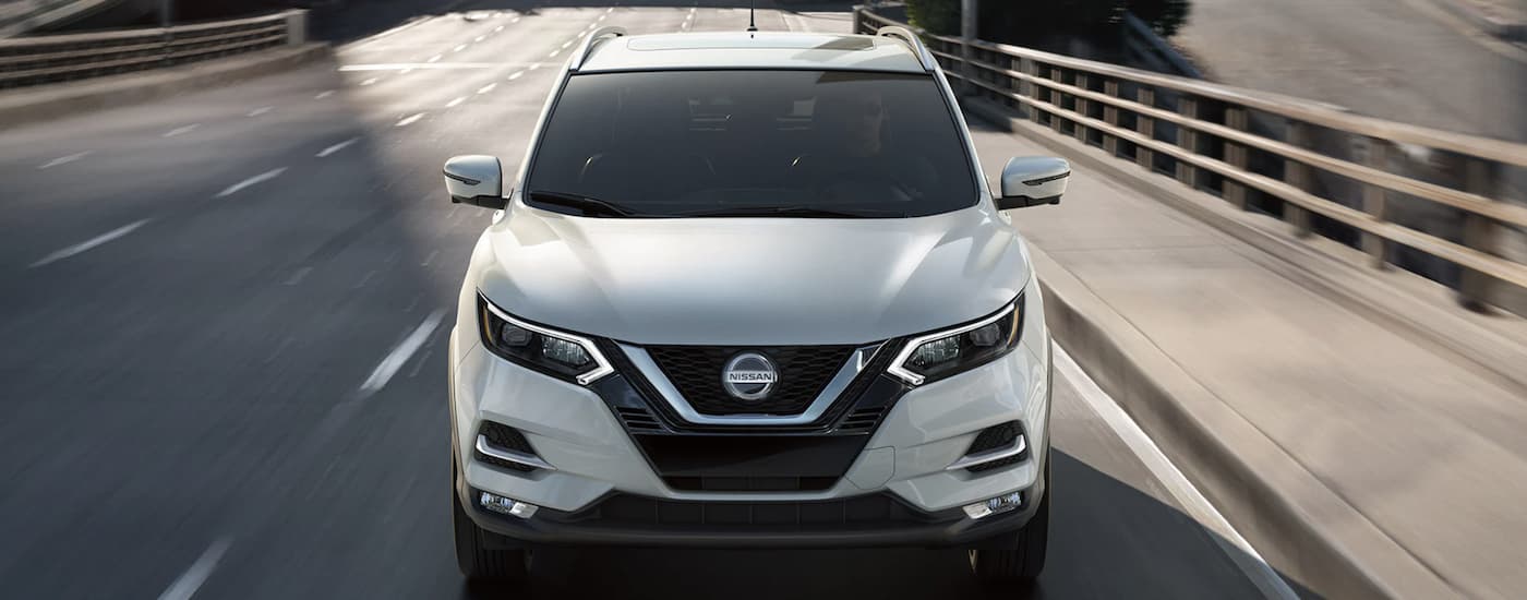 A white 2021 Nissan Qashqai is shown from the front driving on an open road.