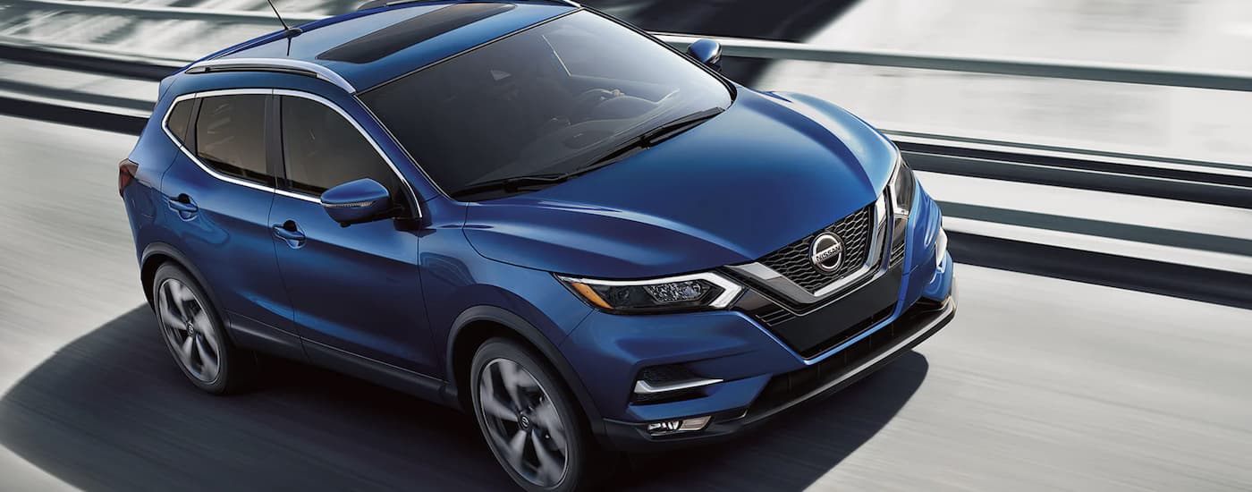 A popular used Nissan Qashqai for sale, a blue 2021 Nissan Qashqai, is shown from above driving on an open road.