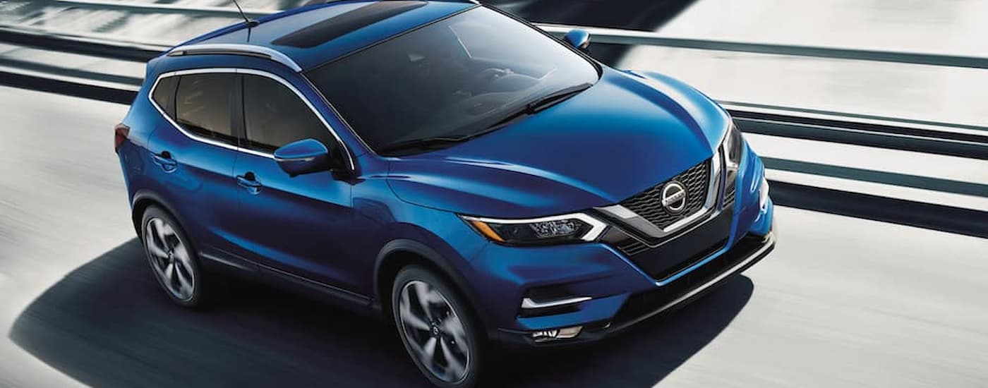 A blue 2022 Nissan Qashqai is shown driving on an open highway.