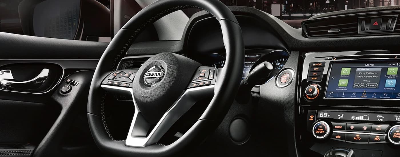 The steering wheel and center console in a 2022 Nissan Qashqai is shown.