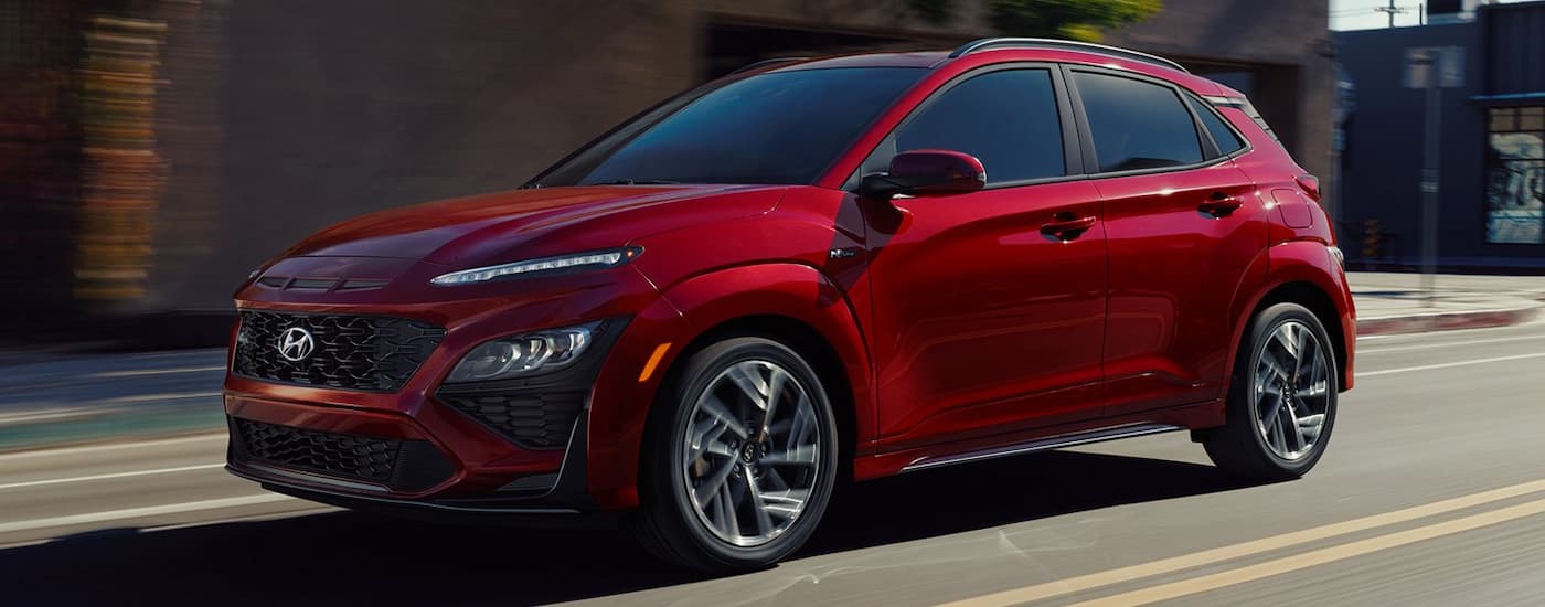 A red 2022 Hyundai Kona N-Line is shown driving on a street after viewing a used Hyundai Kona for sale.