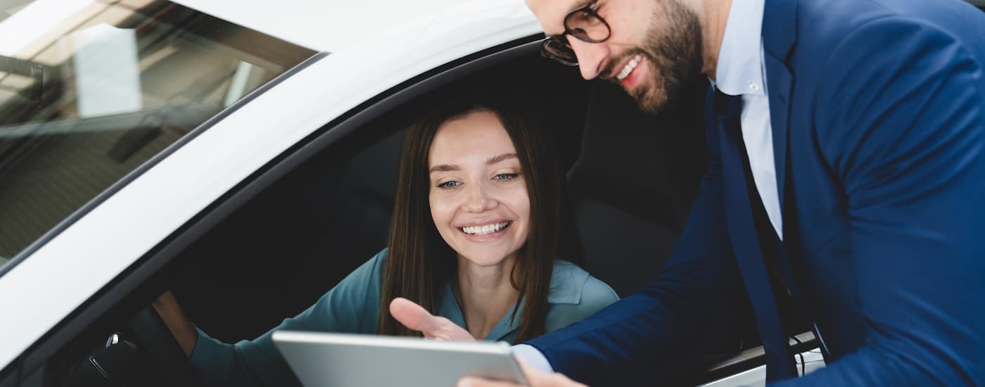A car salesman is shown speaking to a customer about bad credit car loans.