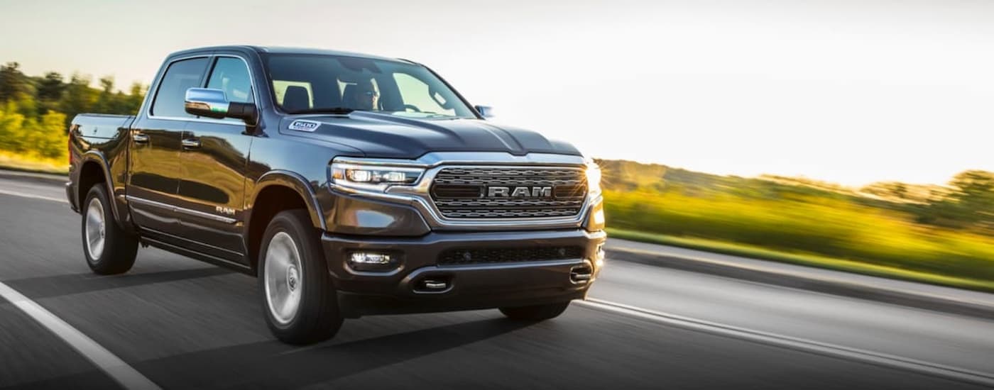 A grey 2019 Ram 1500 is shown driving on an open road next to a grassy field.