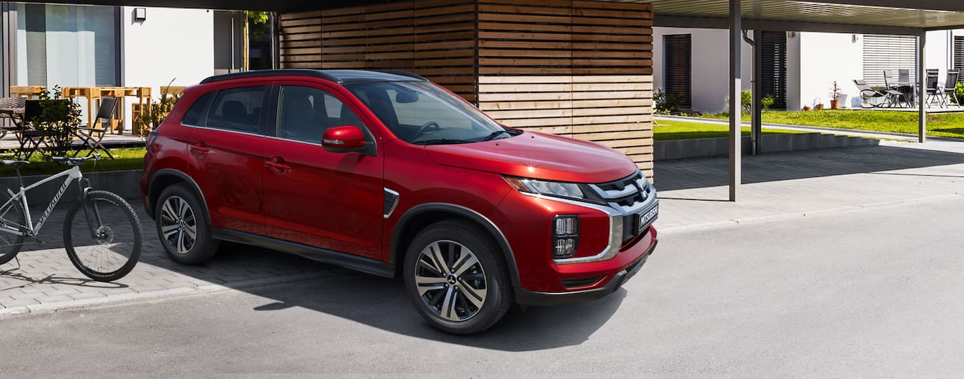 A red 2022 Mitsubishi RVR is shown parked underneath an overhang near an apartment building.