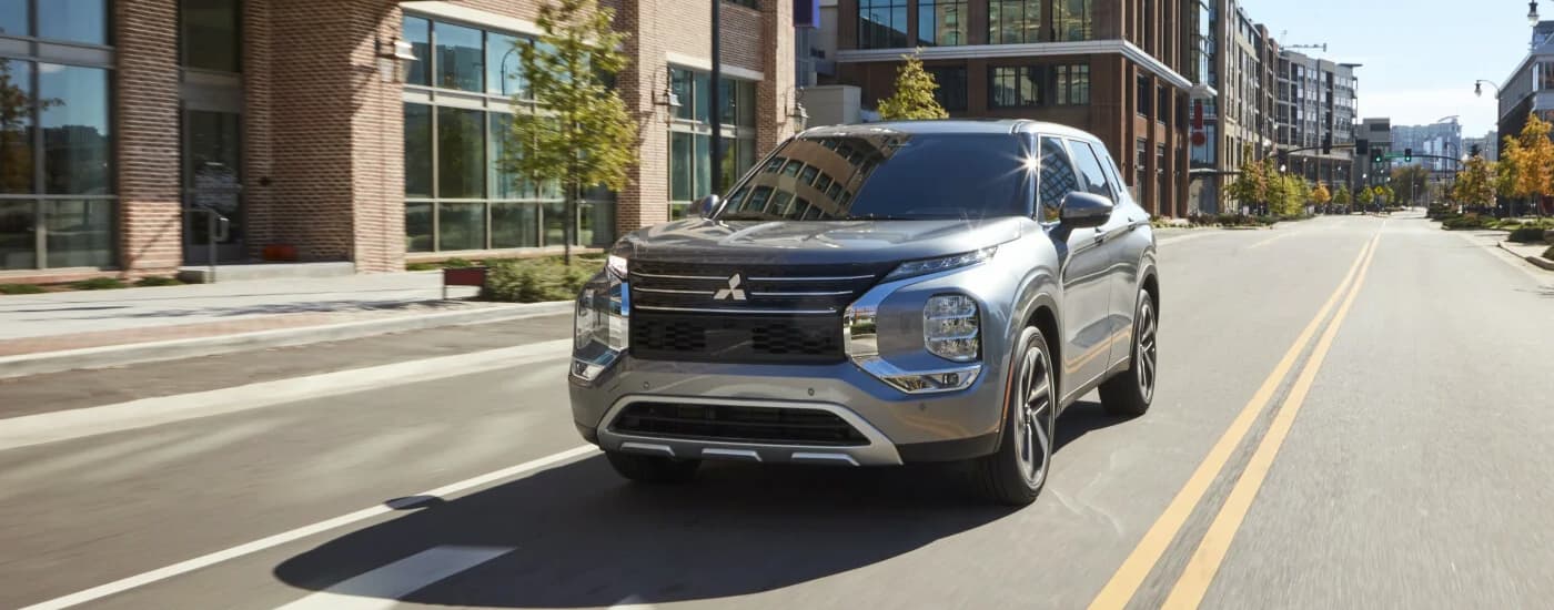 A silver 2022 Mitsubishi Outlander is shown driving through a city after viewing SUVs for sale in Edmonton. 