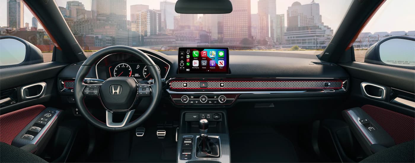 The red and black interior of a 2023 Honda Civic Si, with infotainment screen and digital dash