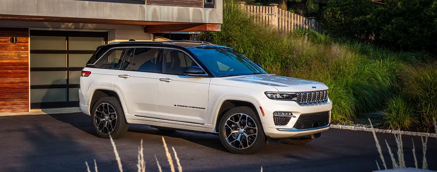 A white 2023 Jeep Grand Cherokee is shown parked in a driveway.