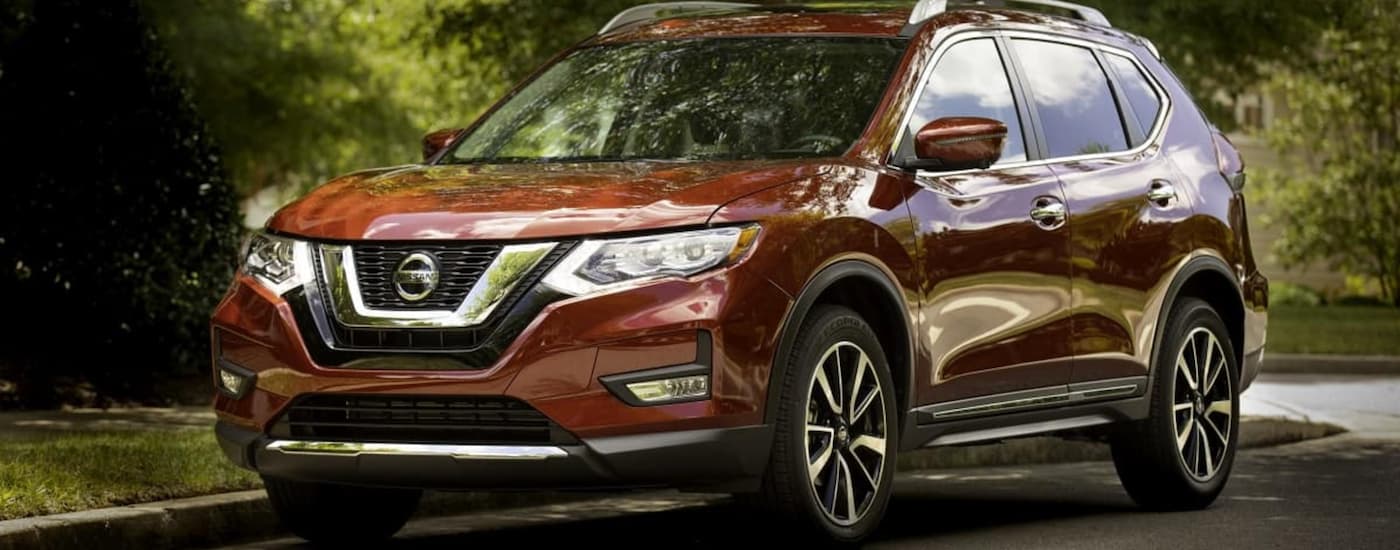 A red 2017 Nissan Rogue is shown parked on the side of a tree-lined road.