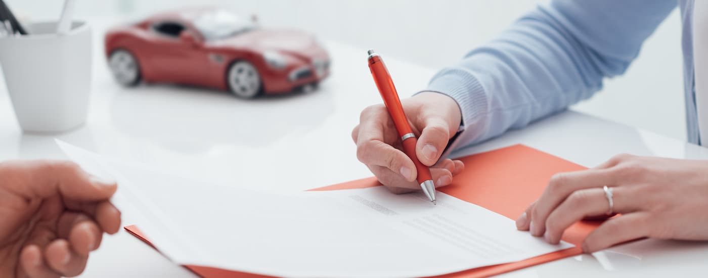 A person is shown signing paperwork about bad credit car loans in Edmonton.