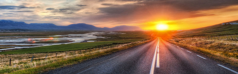 Two-lane highway through rural Tennessee with hills, marsh, and the sun setting.