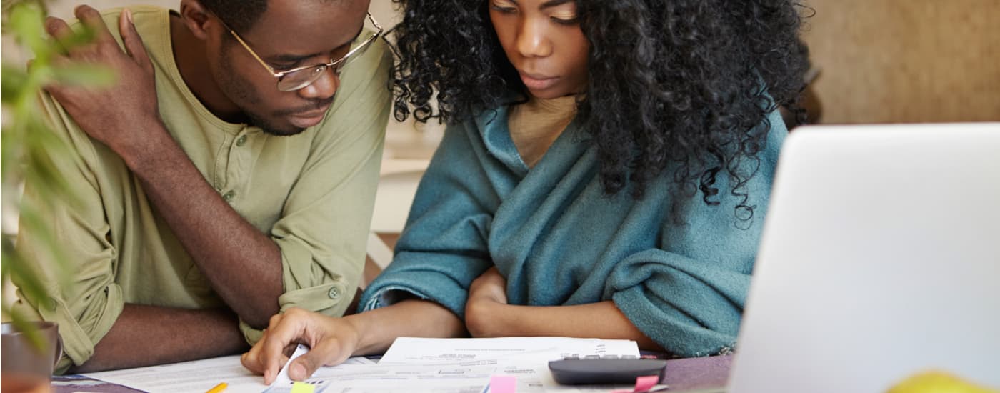 A couple is shown filling out paperwork about their car value before selling it to a dealer.