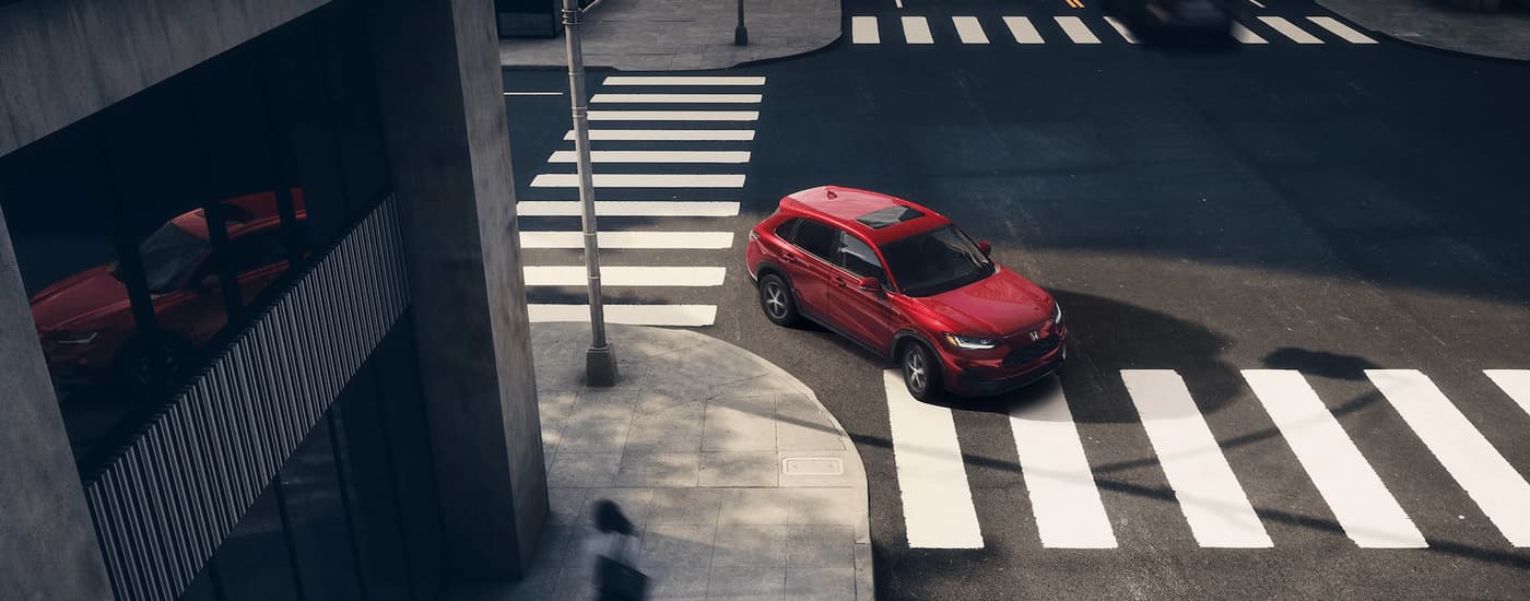Aerial view of a red 2023 Honda HR-V making a turn through a city intersection.