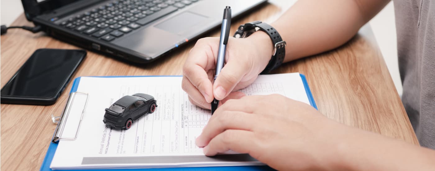 A person is shown filling out paperwork so they can sell their car.