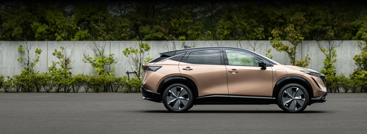 Nissan ARIYA parked, trees in the background