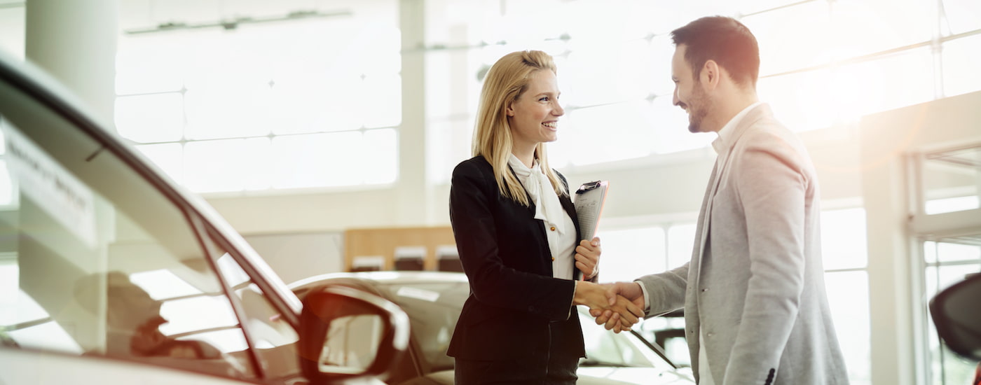 A customer is shown talking to a salesperson about selling their car.