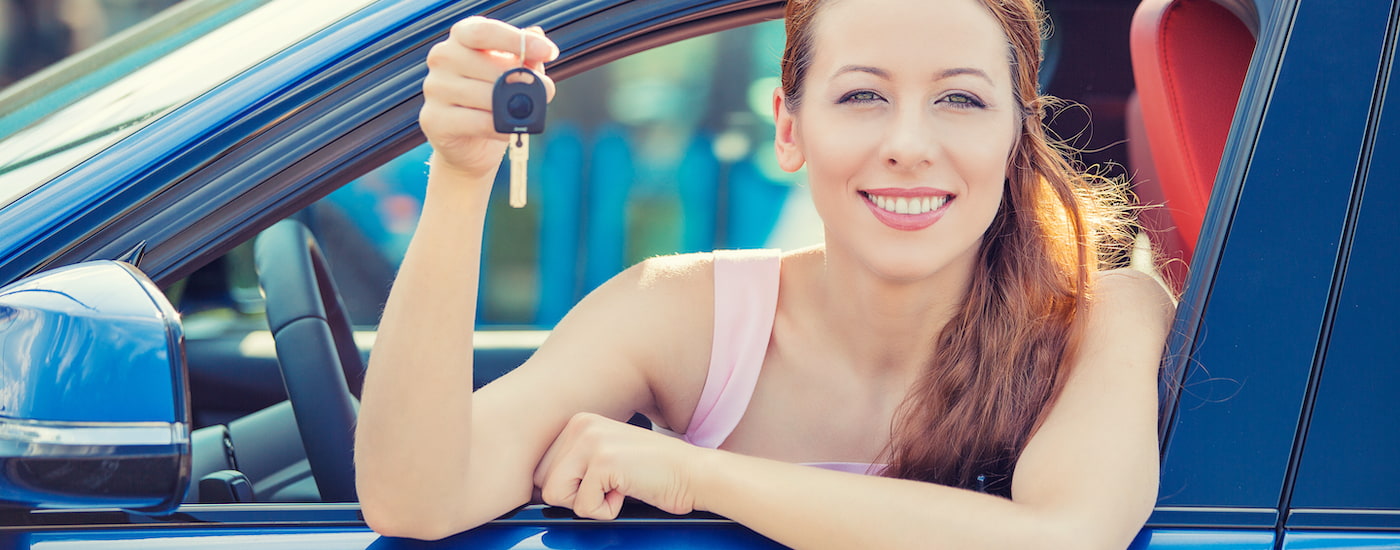 A person is shown holding a car key out the window of a vehicle.
