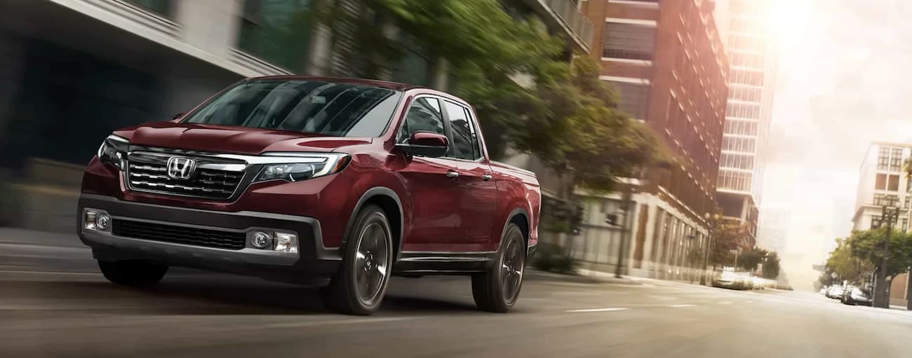 A red 2020 Honda Ridgeline RTL-E drives through the city after leaving a certified pre-owned Honda dealer.