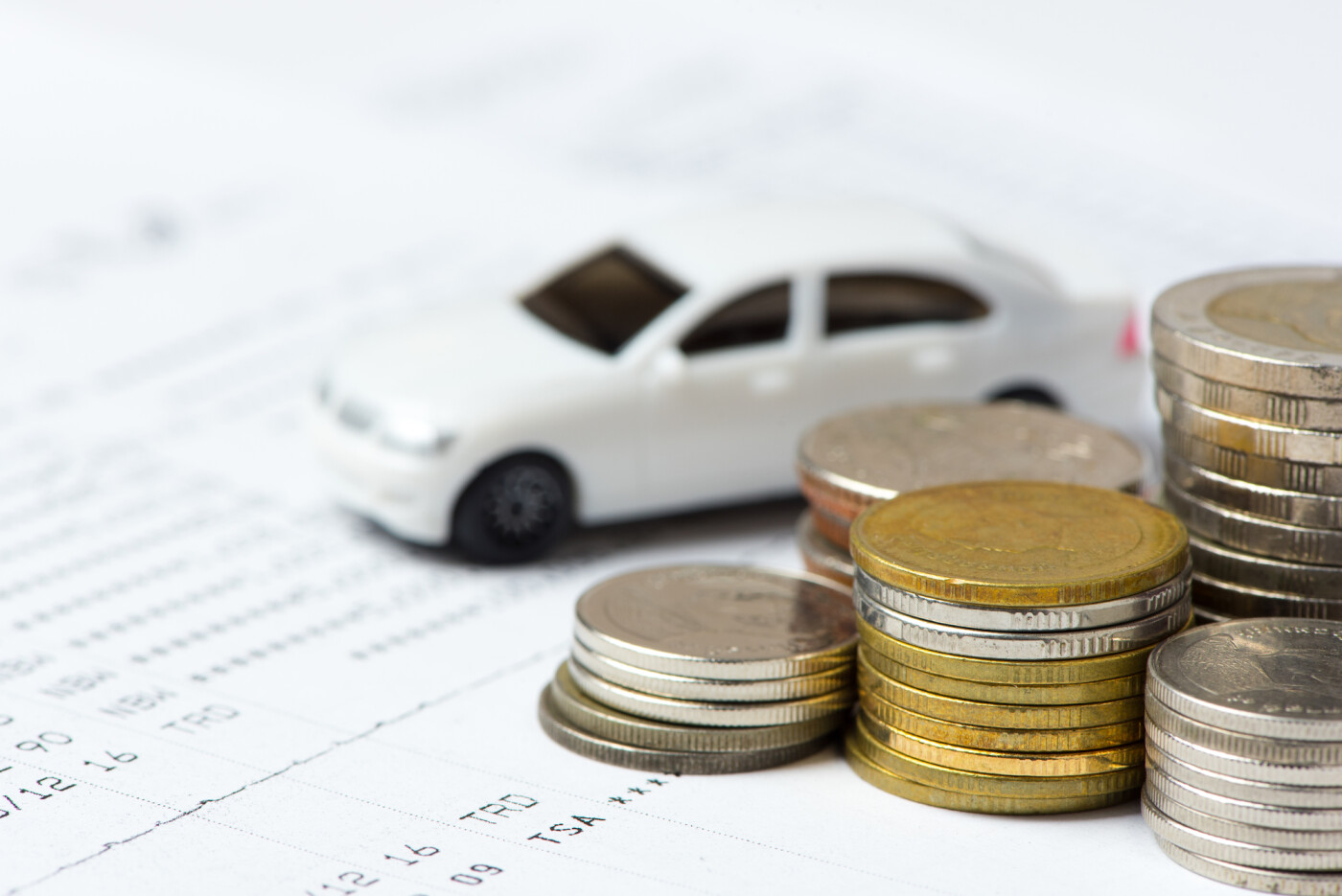 Tiny car with coins and finance paperwork