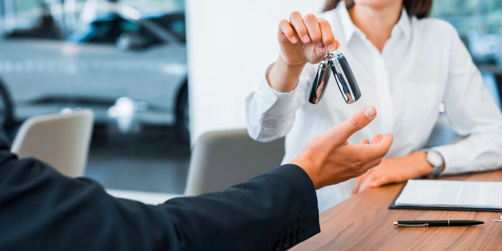 Car dealer giving car key to buyer