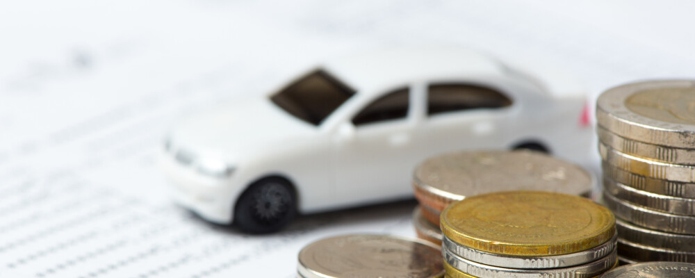 Tiny car with coins and finance paperwork