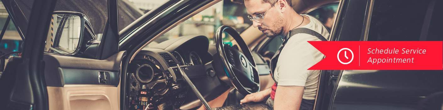Bespectacled service guy sitting in car with computer