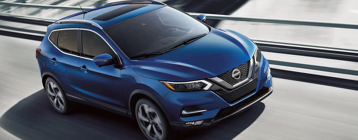 A blue 2022 Nissan Rogue Sport is shown driving on a city highway.