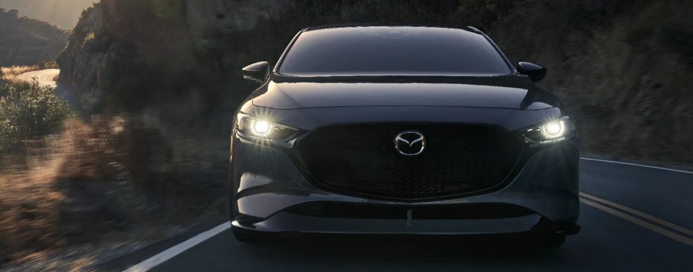 A grey 2022 Mazda3 is shown driving on a mountain road.