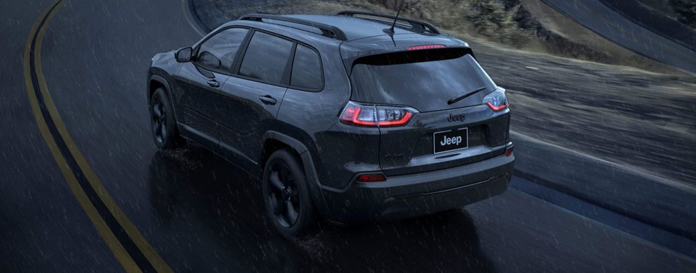 A grey 2023 Jeep Cherokee Altitude Lux is shown driving though the rain.