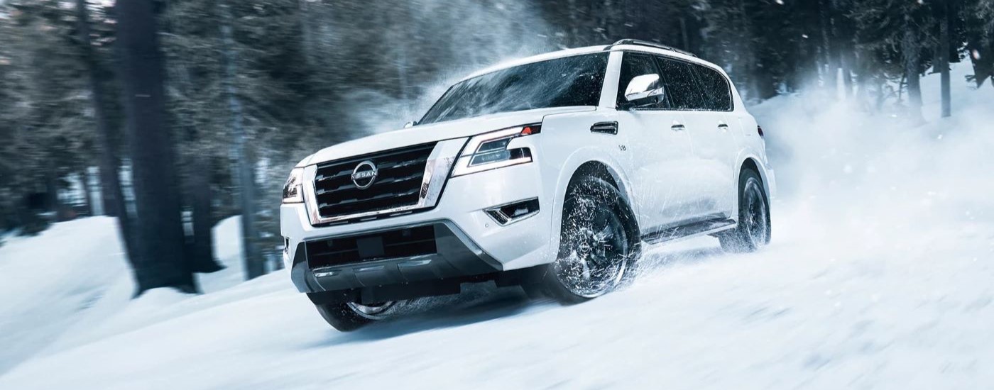 A white 2023 Nissan Armada Platinum is shown driving through snow.
