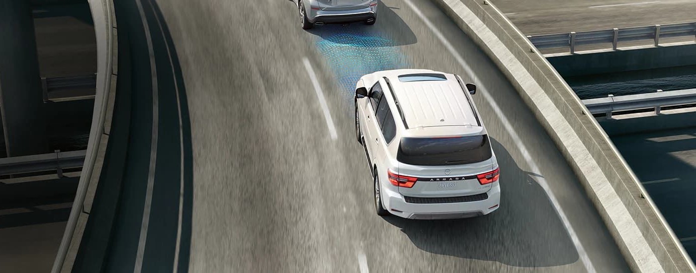 A white 2023 Nissan Armada Platinum is shown on a highway with simulated sensor lines.