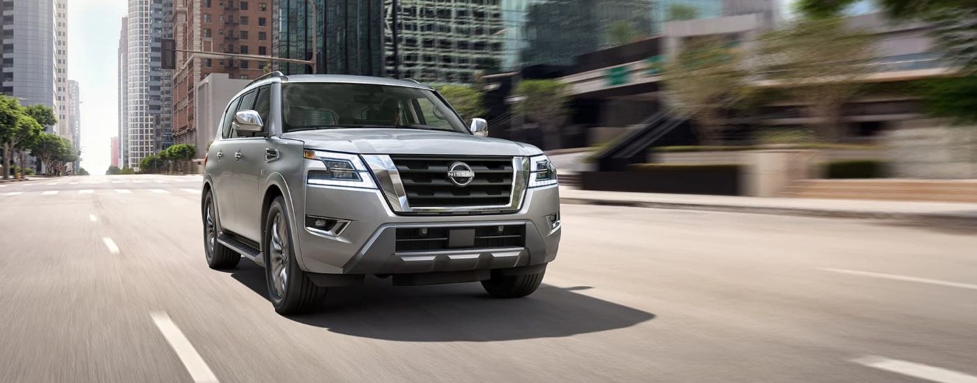 A silver 2023 Nissan Armada for sale is shown driving on a city street.