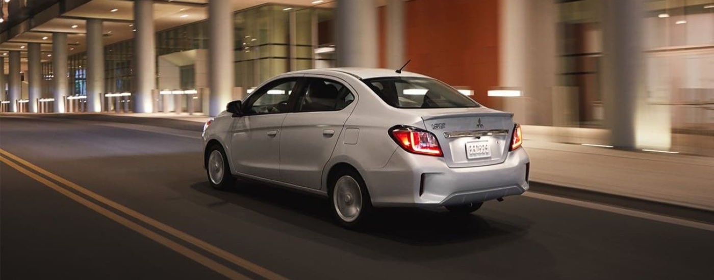 A silver 2021 Mitsubishi Mirage G4 is shown driving on a city street at night.