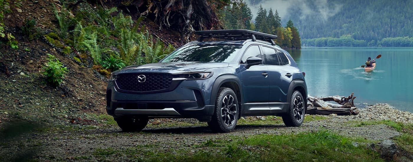 A blue 2023 Mazda CX-50 is shown parked next to a lake after leaving a Bellevue Mazda dealer.