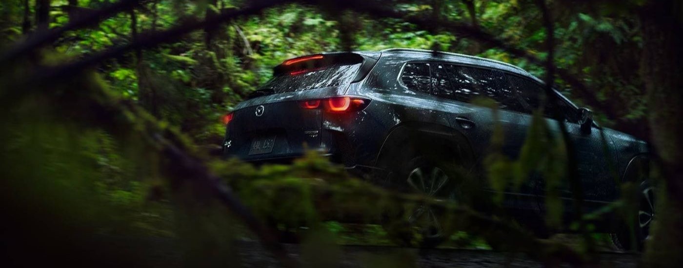 A close up shows a 2023 Mazda CX-50 driving through the woods.