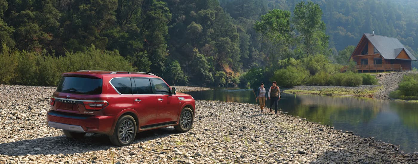 A red 2023 Nissan Armada Platinum for sale is shown parked near a river.